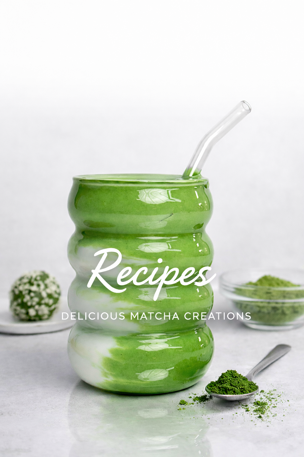 Green matcha drink in a glass with a straw, surrounded by matcha powder and a spoon on a white background.